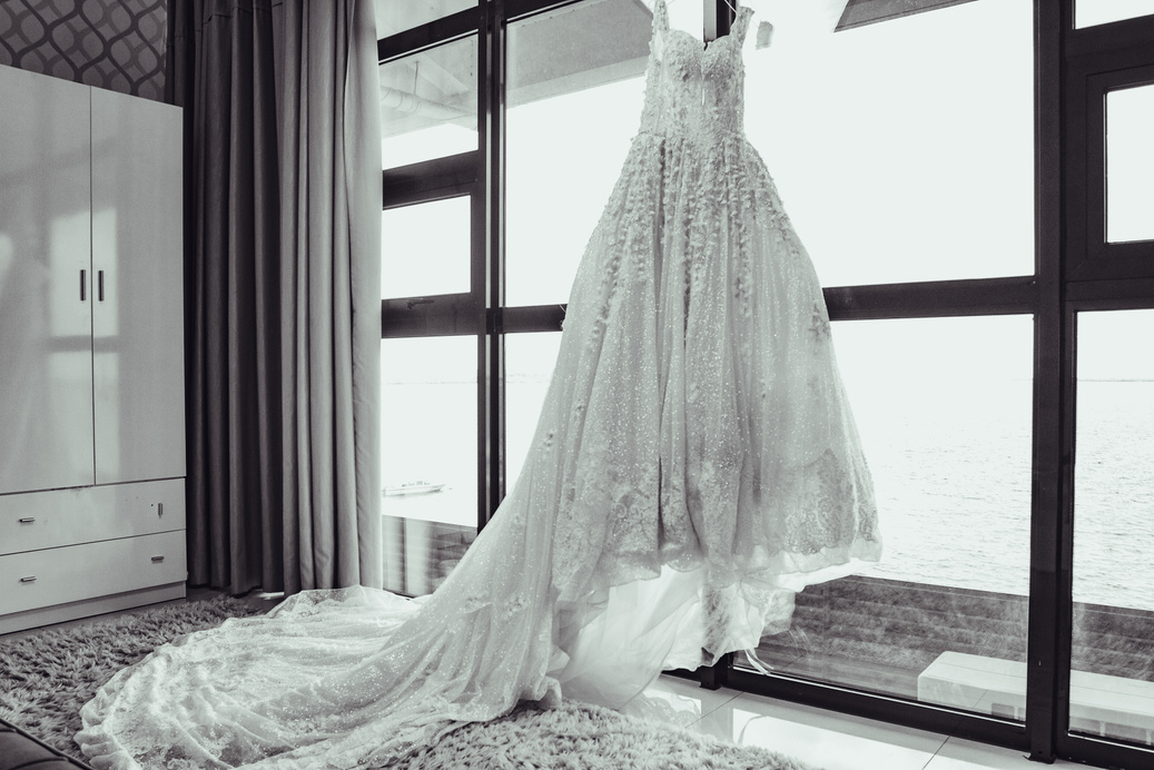 Grayscale Photo of White Wedding Dress on Window
